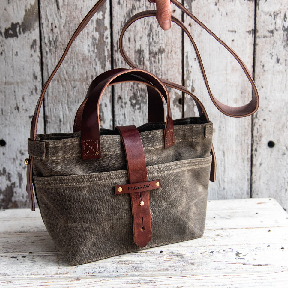 Black waxed canvas tote bag with leather bottom handles and cross body strap